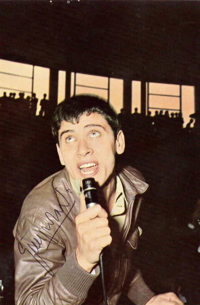 Cartolina autografata Gianni Morandi giovane in concerto con microfono anni '60 – autografo originale pennarello nero sulla figura – 14,5x10 cm – condizioni Excellent