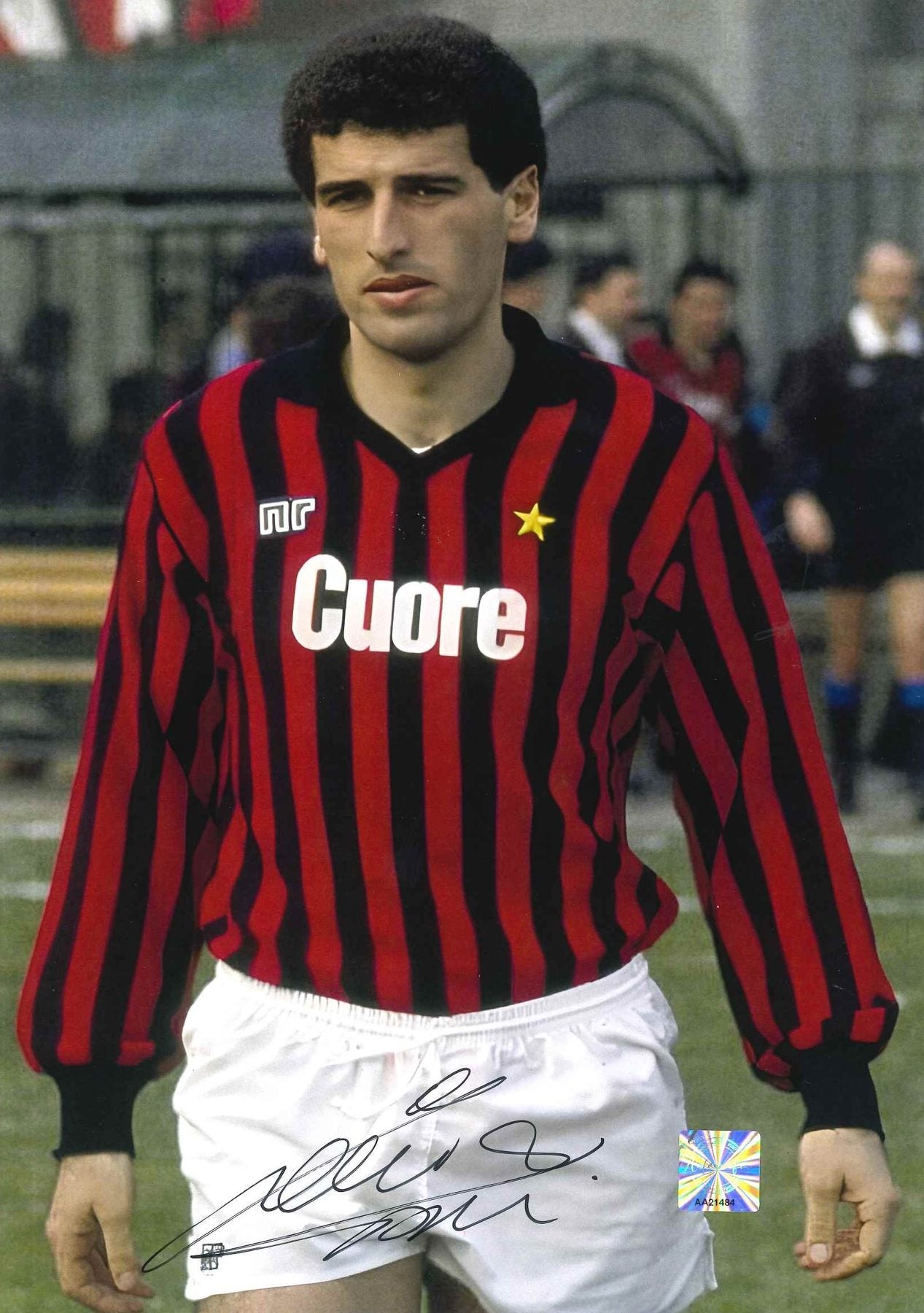 Fotografia autografata Mauro Tassotti Milan Home 1983/84 maglia Ennerre rossonera strisce verticali sponsor Olio Cuore stella dorata pantaloncini bianchi posa pre-partita bollino Witnessed AA21484 – autografo pennarello nero – 29,6x20,9 cm