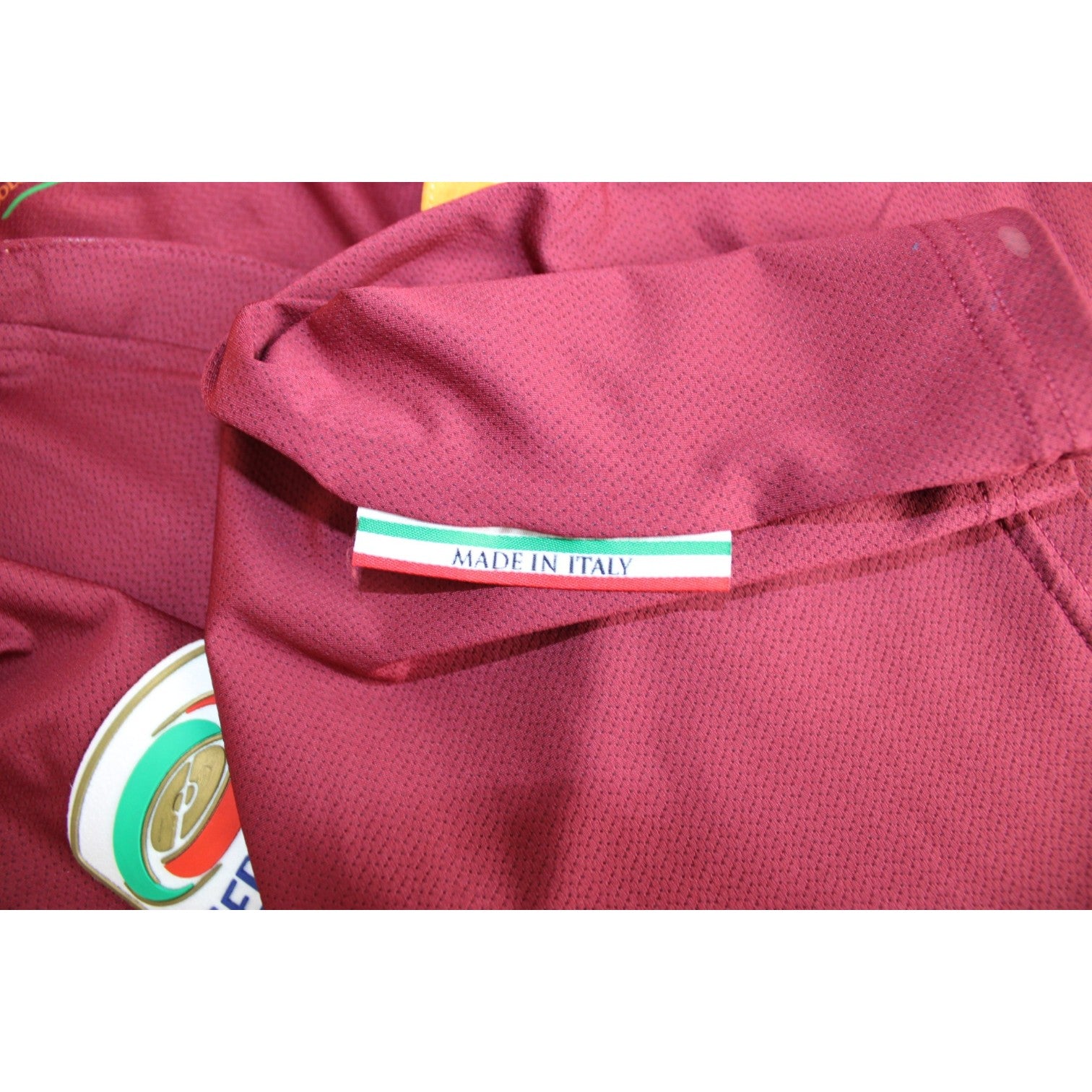 Dettaglio etichetta Made in Italy maglia AS Roma Home 2013/14 produzione in-house tessuto traforato rosso pompeiano patch Serie A TIM