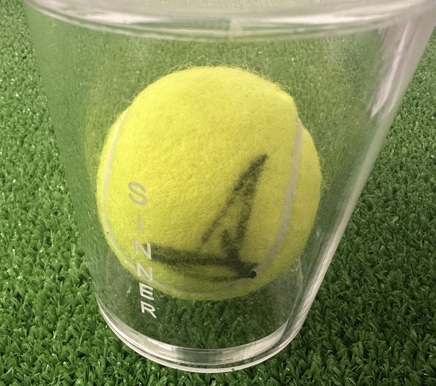 Dettaglio autografo Jannik Sinner su pallina da tennis – pennarello nero – teca plexiglass – pezzo unico da collezione
