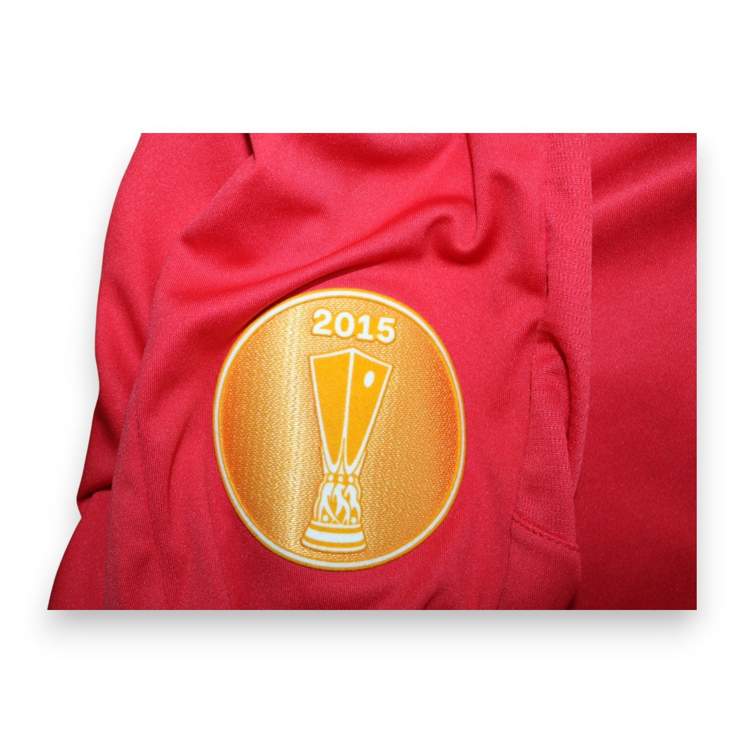 Dettaglio patch UEFA Europa League Winner 2015 maglia Siviglia 2015-16 – coppa dorata su sfondo oro – detentori titolo stagione 2015-16