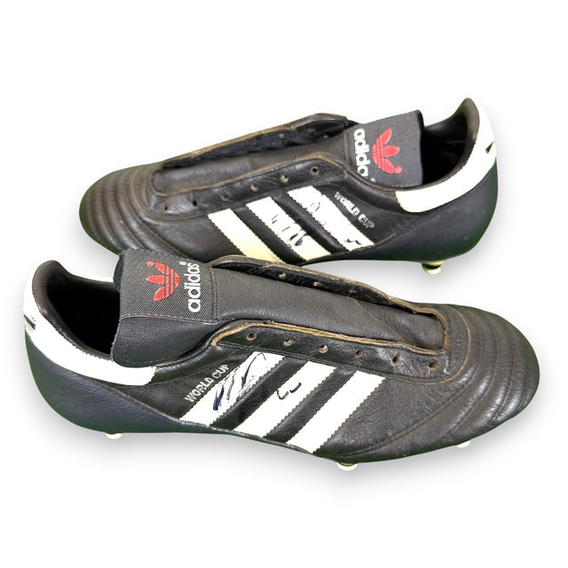 Coppia scarpe da calcio autografate Andreas Brehme – Adidas World Cup nere tre strisce bianche – taglia 39,5 – autografo originale pennarello nero su entrambe – COA Associazione Autografia incluso