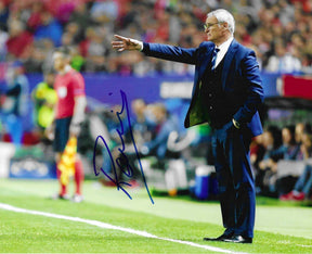 Fotografia autografata Claudio Ranieri allenatore a bordo campo abito blu braccio teso istruzioni squadra stadio illuminato serale Premier League Leicester – autografo originale pennarello blu lato sinistro – 15x20 cm – condizioni Excellent