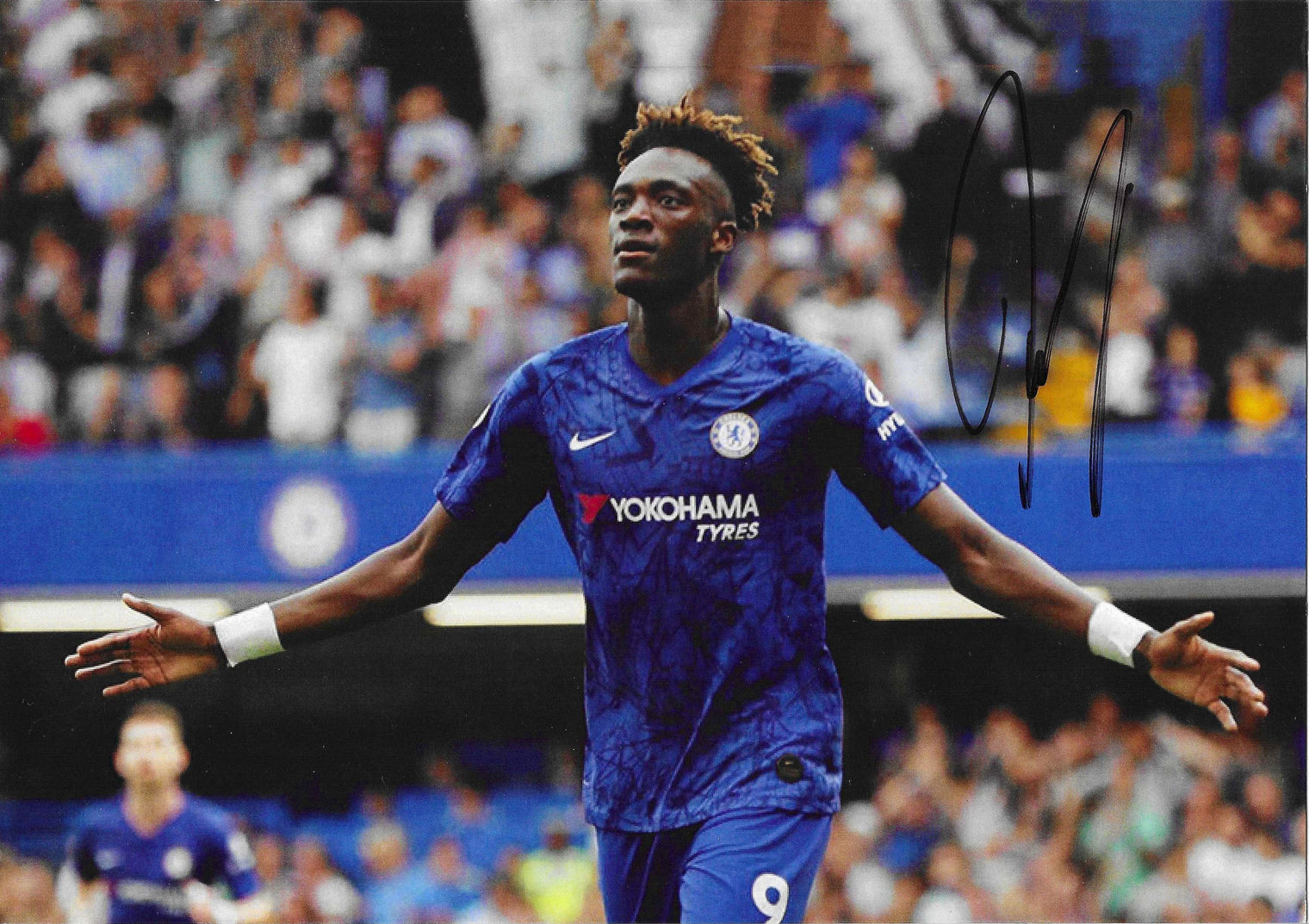 Fotografia autografata Tammy Abraham esultanza braccia aperte maglia Chelsea blu Nike Yokohama Tyres numero 9 Stamford Bridge stagione 2019-2020 – autografo originale pennarello nero in alto a destra – 29,5x20,8 cm – condizioni Excellent