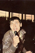 Cartolina autografata Gianni Morandi giovane in concerto con microfono anni '60 – autografo originale pennarello nero sulla figura – 14,5x10 cm – condizioni Excellent