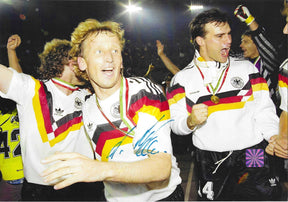 Fotografia autografata Andreas Brehme festa post vittoria Mondiali Italia 1990 tuta Adidas Germania medaglia oro al collo compagni squadra esultanza ologramma sicurezza Associazione Autografia – autografo originale pennarello blu al centro – 29,3x20,5 cm – condizioni Excellent