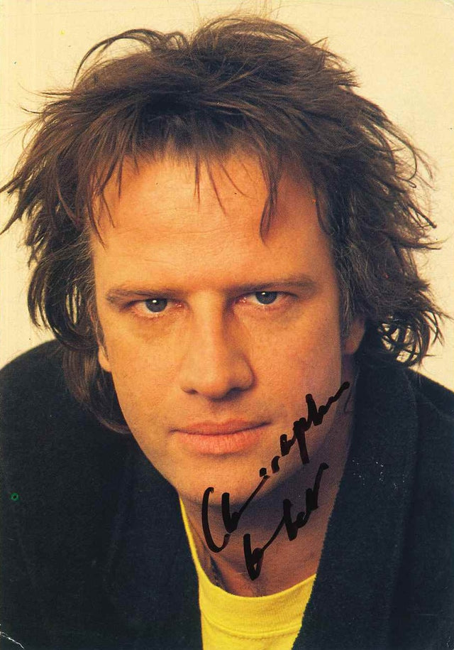 Cartolina autografata Christopher Lambert ritratto a colori anni Novanta capelli lunghi scuri sguardo magnetico t-shirt gialla giacca scura attore Highlander cinema – autografo originale pennarello nero – 16,4x11,4 cm