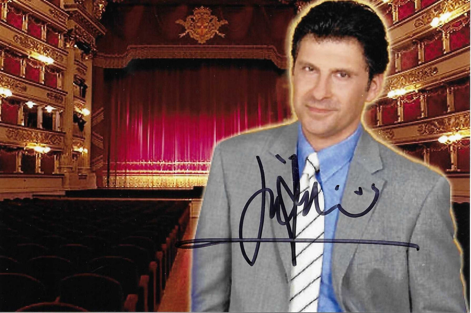 Fotografia autografata Fabrizio Frizzi ritratto a colori abito grigio cravatta righe bianche sfondo Teatro alla Scala Milano illuminato – autografo originale pennarello blu navy ampio al centro – 10x15,2 cm – condizioni Excellent