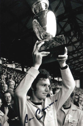 Fotografia autografata Franz Beckenbauer Der Kaiser Bayern Monaco solleva la Coppa dei Campioni anni Settanta tuta bianca Adidas bianco e nero – autografo pennarello blu – 15,5x10 cm