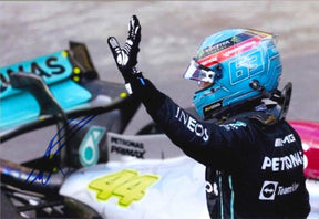Fotografia autografata George Russell Mercedes-AMG Petronas F1 saluto a bordo pista casco azzurro numero 63 Monster Energy tuta nera INEOS Petronas IWC – autografo originale pennarello blu – 29x20 cm