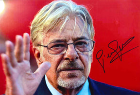 Fotografia a colori autografata Giancarlo Giannini su sfondo rosso – attore con occhiali e mano alzata in saluto – autografo originale pennarello nero – Excellent
