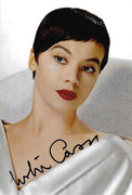 Fotografia autografata Leslie Caron ritratto a colori capelli corti scuri caschetto sguardo intenso labbra rosse abito bianco satinato Hollywood anni 50 – autografo originale pennarello nero in basso ampio – 18,8x12,2 cm – condizioni Excellent