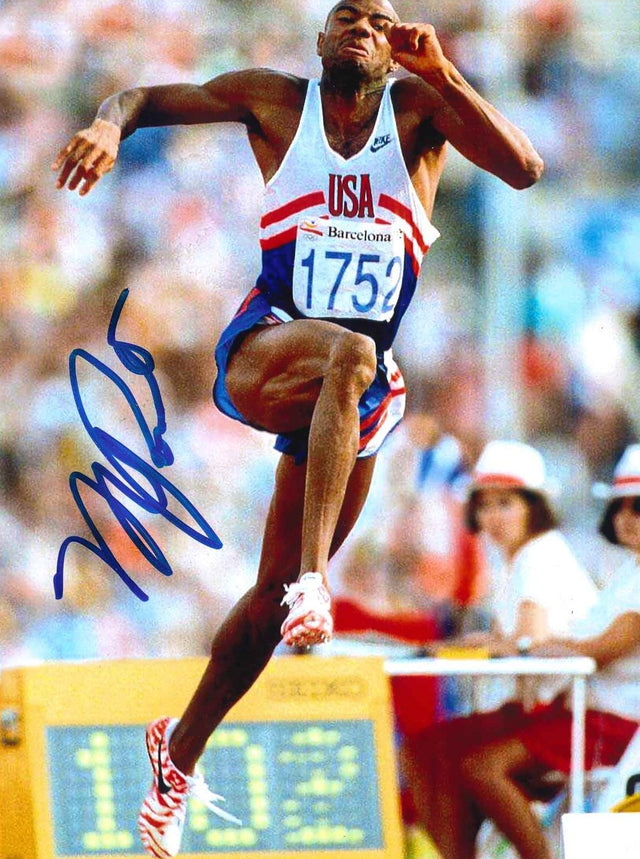 Fotografia autografata Mike Powell salto in lungo Barcellona 1992 – casacca USA pettorale 1752 in volo – autografo originale pennarello blu – condizioni Excellent
