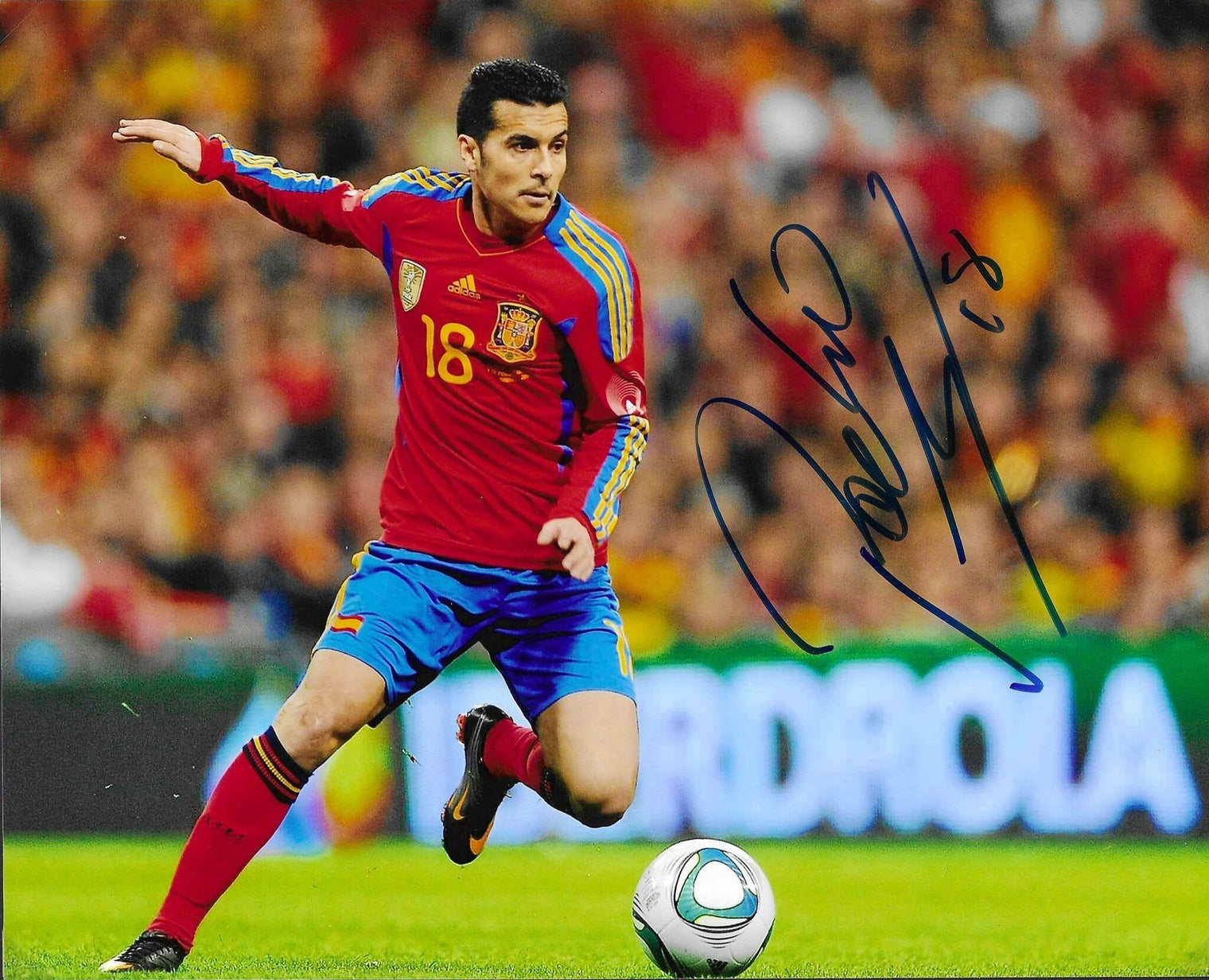 Fotografia autografata Pedro Rodríguez azione in corsa maglia Nazionale Spagna Adidas rossa blu numero 18 pallone Jabulani sponsor Iberdrola – autografo originale pennarello blu con numero 18 lato destro – 25x20 cm – condizioni Excellent