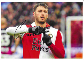 Fotografia autografata Santiago Giménez primo piano esultanza gesto scarpa alzata maglia Feyenoord rossa bianca sponsor Eur Parcs guanti neri – autografo originale pennarello nero lato sinistro – 29,7x21 cm – condizioni Excellent
