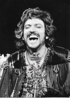 Fotografia con dedica autografata Gigi Proietti primo piano scena teatrale bianco e nero in costume ricco pizzi capelli ricci bocca aperta espressione di riso sfondo nero – dedica autografa originale pennarello scuro al centro – 15x10,5 cm – condizioni Excellent