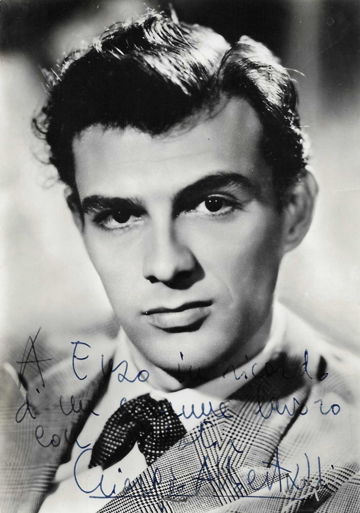Fotografia con dedica autografata Giorgio Albertazzi ritratto bianco e nero press photo anni 50 giovane sguardo intenso capelli ricci ciocca bianca giacca quadri cravatta – dedica originale inchiostro blu tre righe in basso – 15x10,5 cm – condizioni Excellent