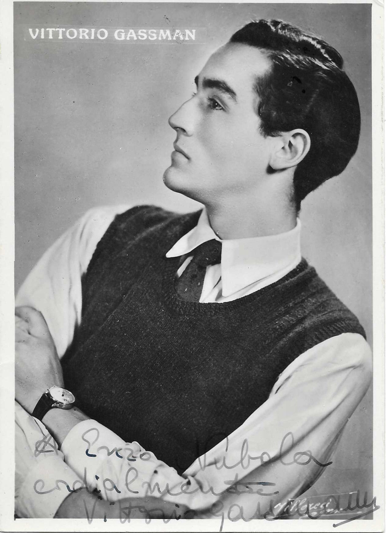 Cartolina ufficiale con dedica autografata Vittorio Gassman ritratto bianco e nero profilo alzato nobile gilet scuro camicia bianca orologio nome stampato in alto – dedica originale inchiostro grigio a Enzo Tubola cordialmente Vittorio Gassman – 15x10,5 cm – condizioni Excellent