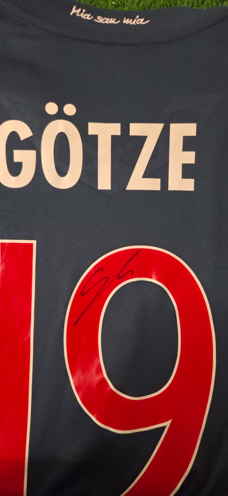 Dettaglio autografo originale Mario Götze pennarello nero direttamente su numero 19 rosso maglia Bayern Monaco Third 2013/14 motto Mia san mia ricamato sotto colletto