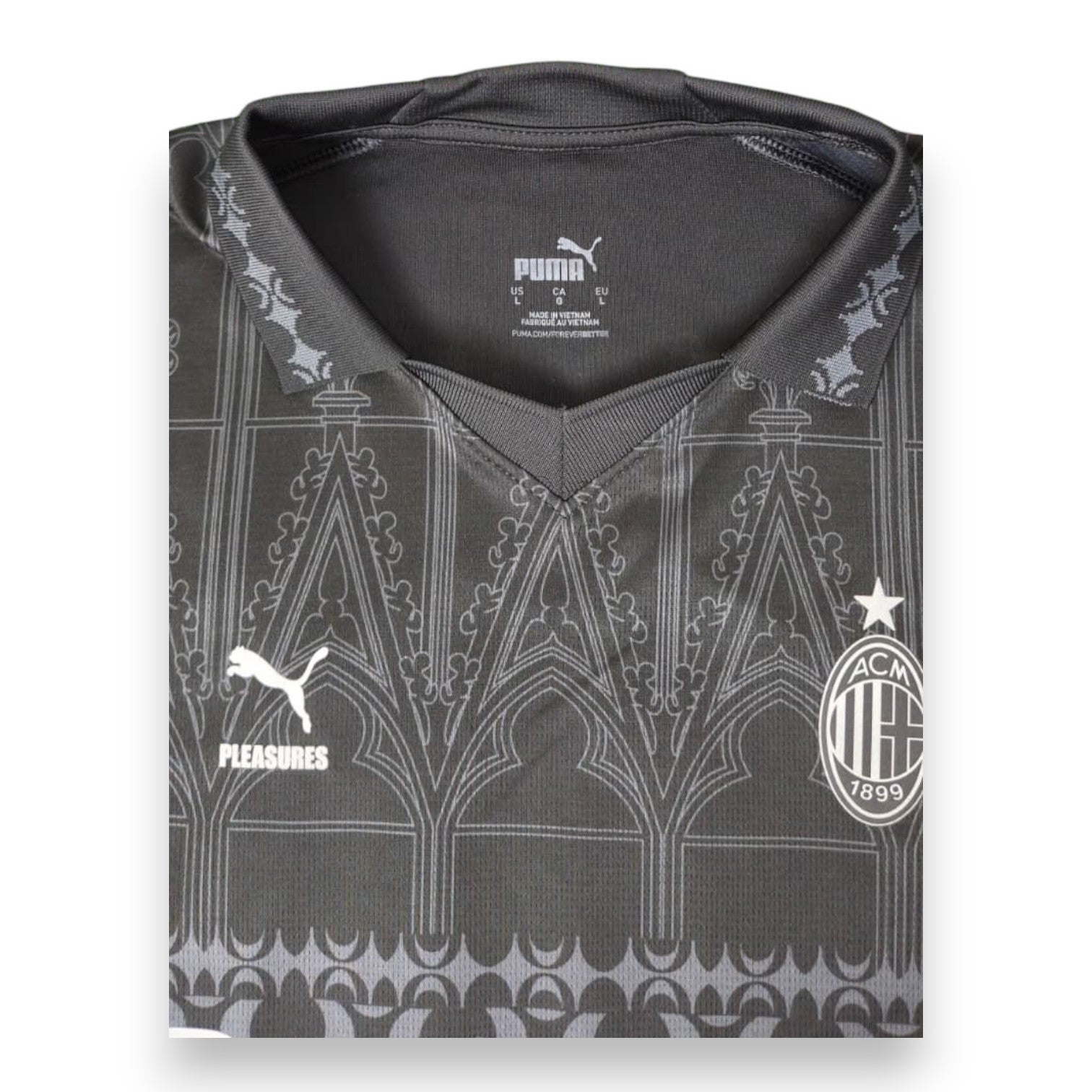 Dettaglio colletto polo e motivo gotico maglia Milan x Pleasures 2023-24 – logo Puma e Pleasures – stemma AC Milan 1899