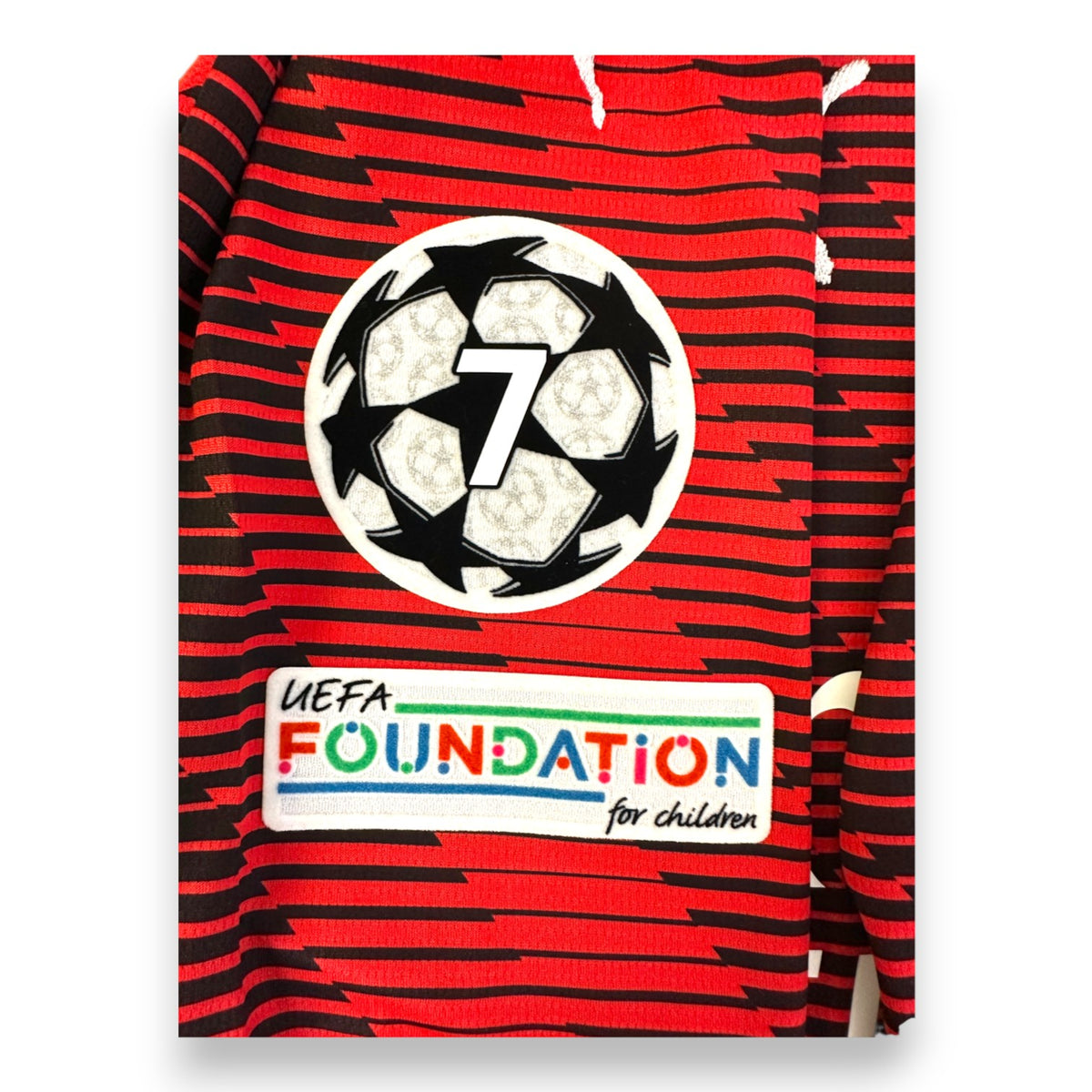 Badge sette Champions League e patch UEFA Foundation for Children su maglia Milan Home 2023-24